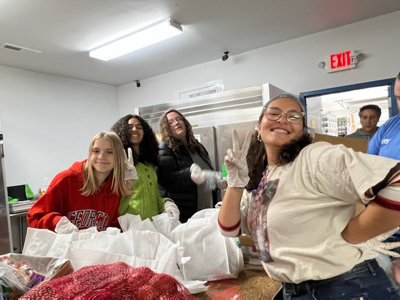 Five youth pose for a picture while they pack Thanksgiving bags for Shiloh Food Pantry.