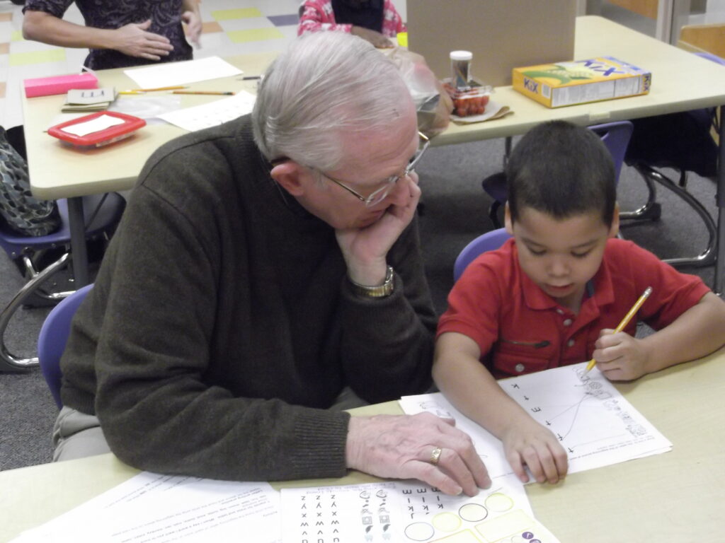 A Member of First Church helps a young boy learn how to read.