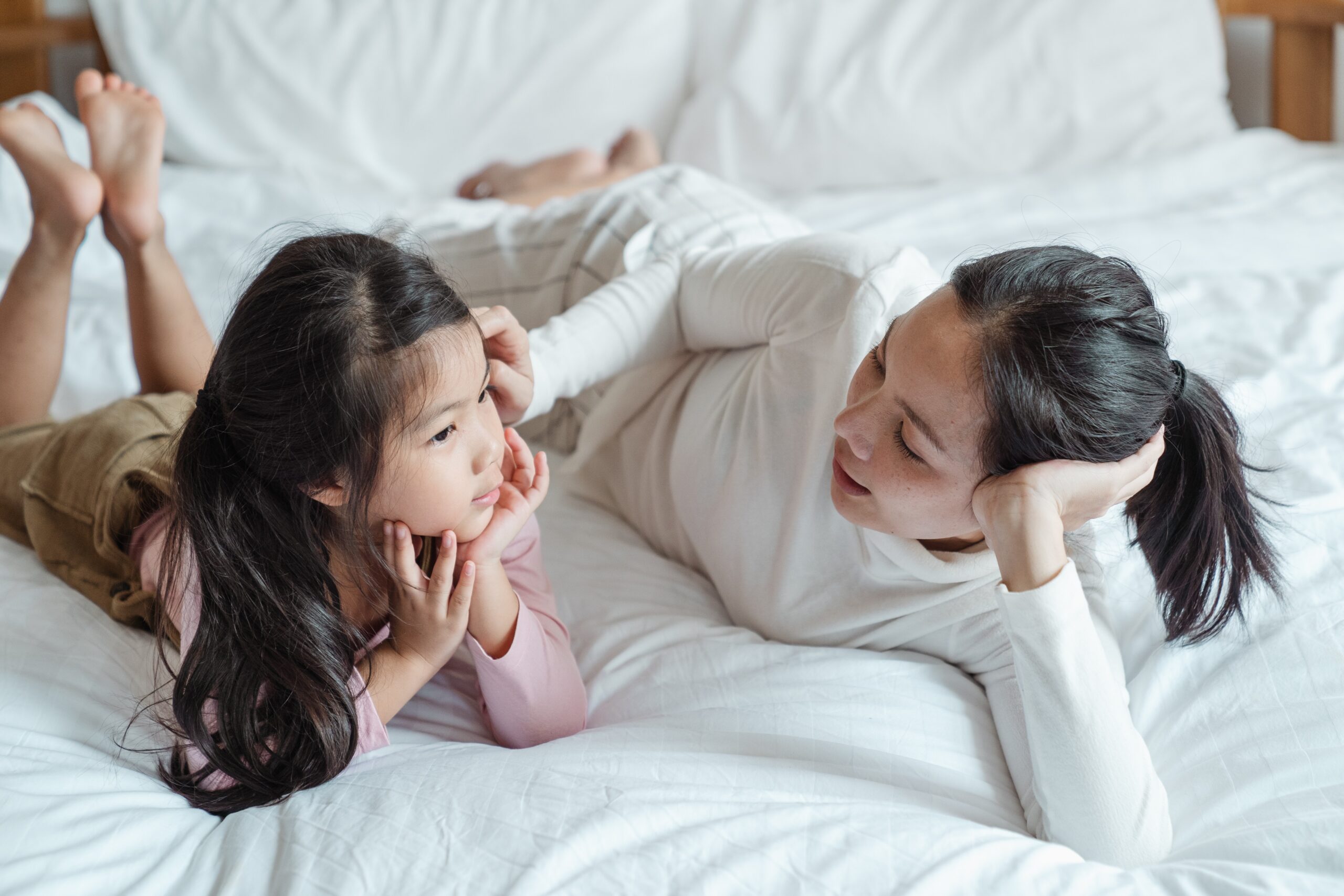 An Asian mother and daughter have a serious discussion on a bed.