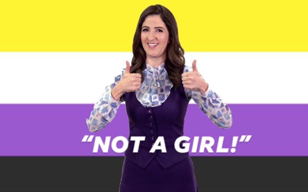 Janet from "The Good Place" stands in front of the non-binary flag, holding two thumbs up.  The text on the image reads "Not a Girl."